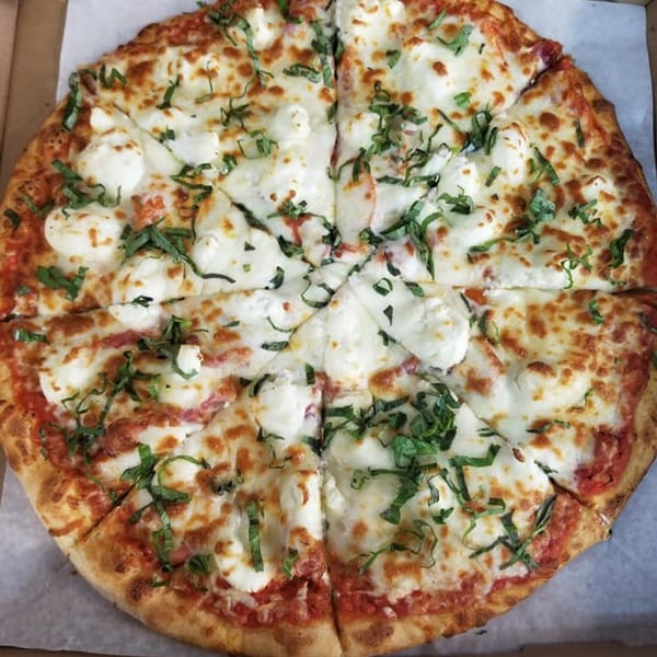 A amore pizza with fresh mozzarella, tomato sauce, and basil, sliced into eight pieces.