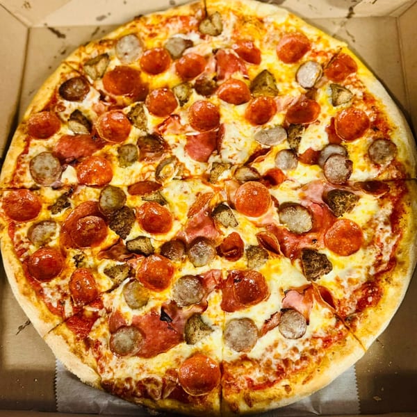 Amore Pizza's large meat lover's pizza, topped with pepperoni, sausage, and ham, in a cardboard box.