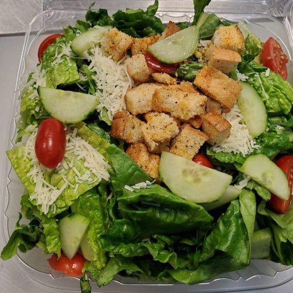A fresh Amore Pizza salad with lettuce, cucumbers, cherry tomatoes, croutons, and shredded cheese.