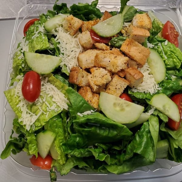 Fresh Amore Pizza salad with lettuce, cucumbers, tomatoes, shredded cheese, and croutons in a plastic container.
