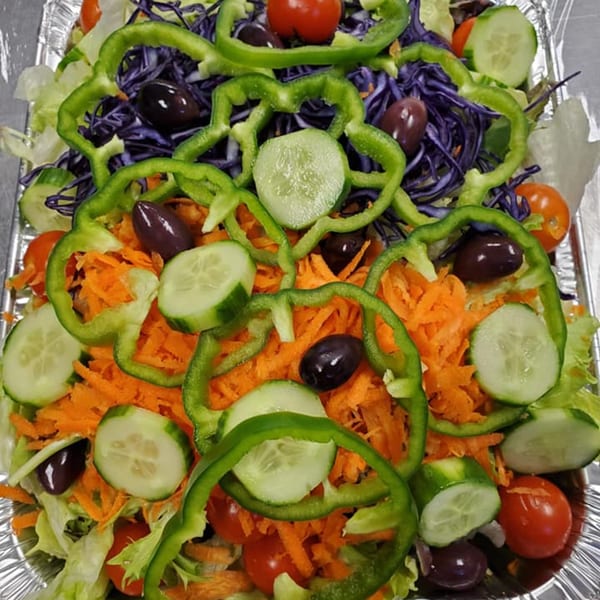 A colorful salad with lettuce, red cabbage, carrots, cucumbers, green peppers, cherry tomatoes, and olives.